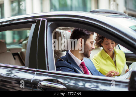 Geschäftsleute, die Schreibarbeit im Auto lesen Stockfoto