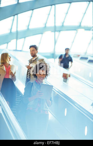 Frau mit digital-Tablette auf Rolltreppe Stockfoto