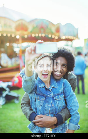 Gemischtrassig junges Paar nehmen Selfie im Vergnügungspark Stockfoto