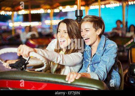 Zwei fröhliche Frauen auf Autoscooter fahren im Freizeitpark Stockfoto
