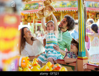 Mädchen mit Teddybär als Trophäe in Angelspiel im Vergnügungspark Stockfoto