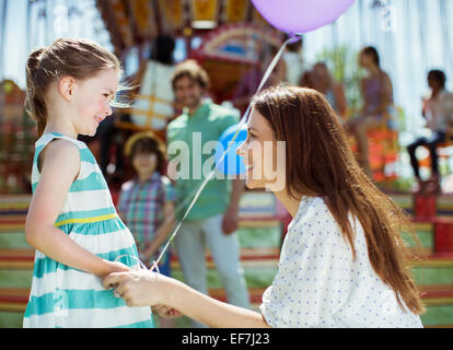 Mutter und Mädchen mit Ballon sahen einander im Vergnügungspark Stockfoto