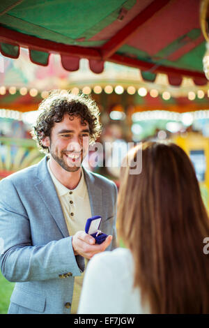 Mann schlägt vor, Freundin im Freizeitpark Stockfoto