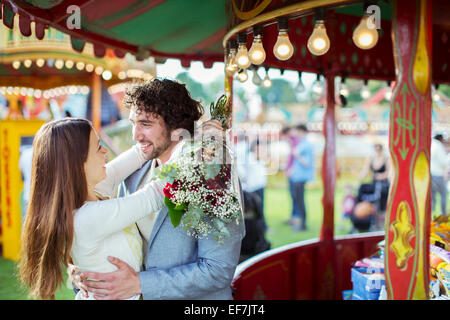 Frau holding Bouquet und umarmte seinen Freund im Vergnügungspark Stockfoto