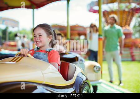 Fröhliches Mädchen auf Karussell im Vergnügungspark Stockfoto