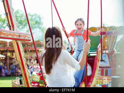 Mutter und Tochter spielen auf Schaukel im Vergnügungspark Stockfoto