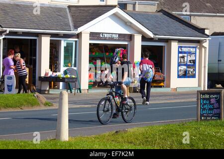 Radfahrer vorbei G. Twentymans speichern berühmt für seine Eis in Allonby, Cumbria, England, UK. Stockfoto