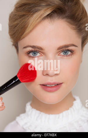 Porträt einer Frau mit Make-up Pinsel auf ihr Gesicht Stockfoto