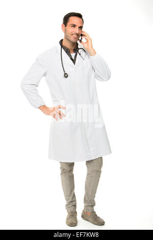 Voller Länge Porträt os einen lächelnden männlichen Arzt mit Stethoskop während der Benutzung eines Mobiltelefons Stockfoto