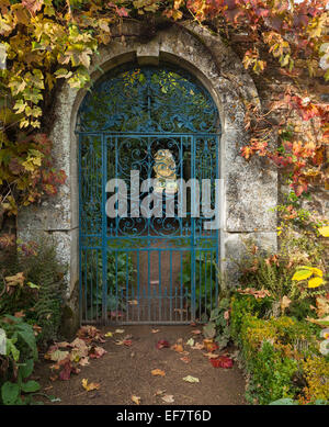 Schmiedeeiserne Tor in einem Cotswold Steinbogen und umrahmt von Weinblättern mit herbstlichen Farbtönen Rousham House, Oxfordshire, England Stockfoto