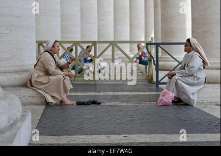 Zwei Nonnen ruhen und sprechen durch die Spalten der Kolonnade in St.-Peter Platzes, Vatikanstadt, Rom, Italien. Stockfoto