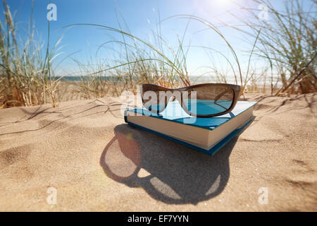 Buch und Sonnenbrille am Strand Stockfoto