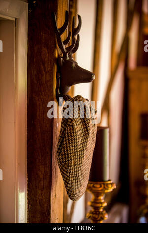 Eine flache Kappe, die an einem Hirsch-förmigen Haken hängt. Stockfoto