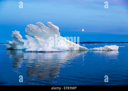 Kanada, Territorium Nunavut, Mondaufgang hinter schmelzenden Eisberg in gefrorenen Kanal am nördlichen Rand der Hudson Bay in der Nähe von Polarkreis Stockfoto