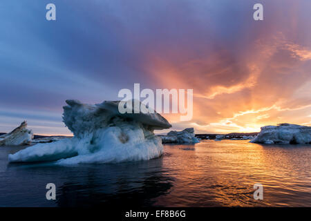 Kanada, Nunavut, Territorium, Mitternacht Abendsonne leuchtet Wolken über schmelzenden Eisberg im Hurd-Kanal in der Nähe von Vansittart Insel Ca Stockfoto