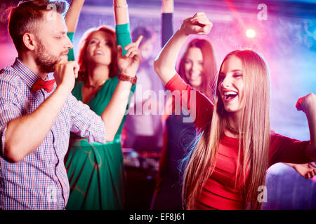 Glückliches junges Paar und ihre Freunde auf Hintergrund zusammen tanzen im Nachtclub Stockfoto