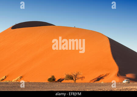 Fünf Touristen Fuß auf der Oberseite Riesen orange Düne 45 in Sossusvlei, Namib-Wüste, Namibia, Afrika Stockfoto