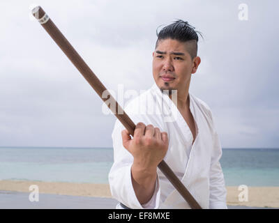 Fumiya Matayoshi mit Bo Personalschulung in Kobudo / Karate am Strand in Okinawa Japan. Stockfoto