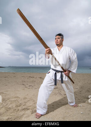 Fumiya Matayoshi mit Eku (Ruder) Ausbildung in Kobudo / Karate am Strand in Okinawa Japan. Stockfoto