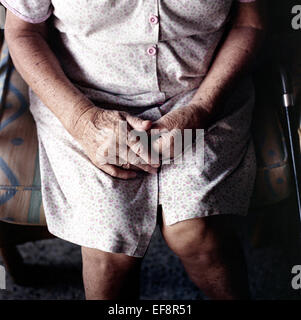 Ältere Frau sitzt mit gefalteten Händen Stockfoto
