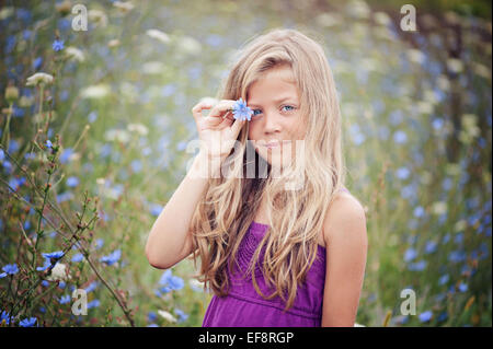 Porträt der jungen Mädchen stehen auf Chicorée-Gebiet, die eine Blume Stockfoto