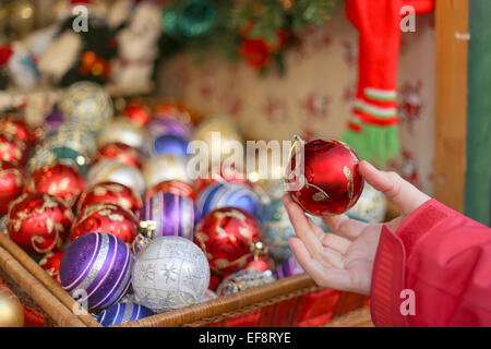 Spanien, Barcelona, Fira de Santa Lucia, Hand halten rote Weihnachtskugel mit anderen Kugeln im Hintergrund Stockfoto