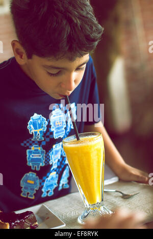 Porträt des Jungen trinken Orangensaft mit Trinkhalm Stockfoto