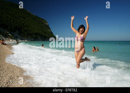 Italien, Marken, Sirolo, glückliche schwangere Frau am Strand Stockfoto