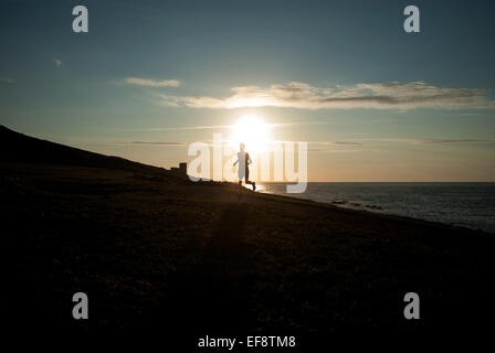 Silhouette der Mann läuft am Strand bei Sonnenuntergang, Galicien, Spanien Stockfoto