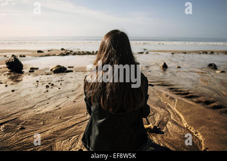 Rückansicht einer Frau, die am Strand sitzt und die Aussicht betrachtet, Deauville, Lisieux, Calvados, Basse-Normandie, Frankreich