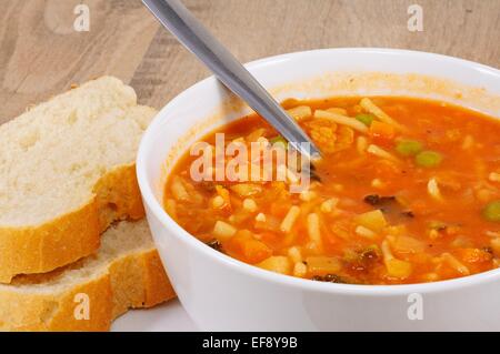 Hausgemachte vegetarische Minestrone-Suppe mit Brot serviert. Stockfoto