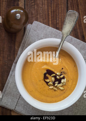 Vegane Kürbis Cremesuppe mit Kokosmilch, serviert mit Kürbiskernen und Kürbiskernöl. Stockfoto