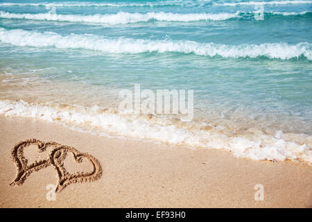 Herzen auf den Strandsand gezeichnet. Stockfoto