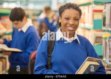 Porträt von lächelnden Studentin hält Bücher in der Bibliothek Stockfoto