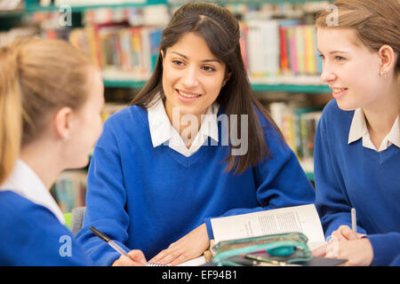 Drei Studentinnen in Bibliothek sitzen und Lächeln Stockfoto