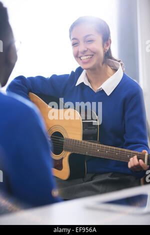 Lächelnde Studentin spielt akustische Gitarre Stockfoto
