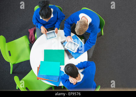 Draufsicht der drei Studenten mit digitalen Brettchen am runden Tisch Stockfoto