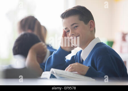 Porträt des Lächelns Grundschule Junge sitzt am Schreibtisch im Klassenzimmer Stockfoto