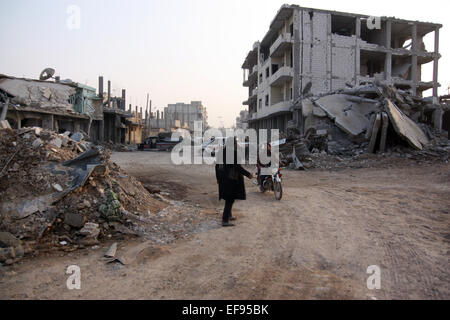 Zwei Männer stehen in einer verlassenen Straße unter zerstörten Autos, Häuser und Geröll dominieren die Szenerie in Stadt Kobane, Syrien, 28. Januar 2015. Kurdische Kämpfer haben es geschafft, die Kräfte des sogenannten IS, islamischen Staat aus der Stadt Kobane zurückzudrängen.  Raketen und Kampfhandlungen, jedoch haben viele Zivilisten getötet und Kobane völlig am Boden zerstört. Foto: Jan Kuhlmann/dpa Stockfoto