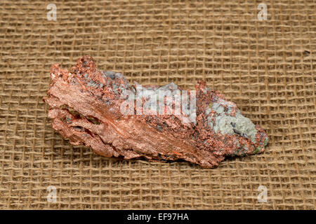 Nahaufnahme einer nativen Kupfer Nugget mit Kristall Verunreinigungen. Studio-Makro. Sackleinen Hintergrund. Probe ist vom oberen Michigan, USA. Stockfoto