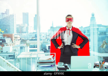 Geschäftsfrau tragen Cape und Maske im Büro Stockfoto