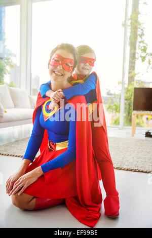 Superhelden-Mutter und Sohn lächelnd in Wohnzimmer Stockfoto