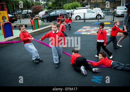 Glücklich lächelnden Kindern auf dem Spielplatz der Grundschule in London W2 Stockfoto