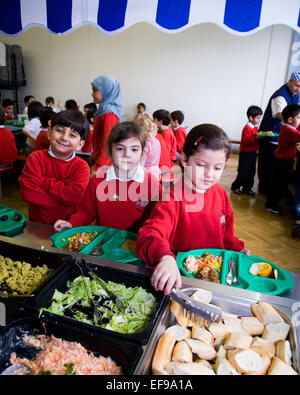 Zur Mittagszeit am UK staatliche Grundschullehrer und Kinder im Grundschulalter in der Grundschule Stockfoto