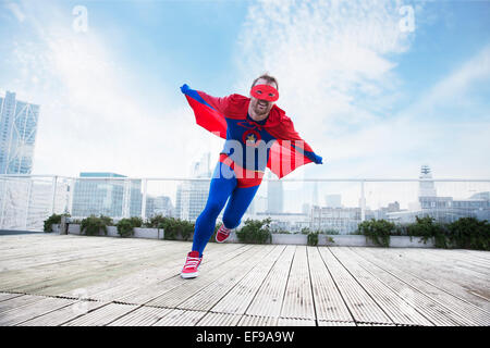 Superheld mit Umhang auf Stadt auf dem Dach ausgeführt Stockfoto