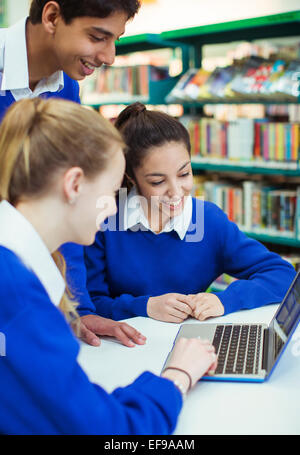 Schüler arbeiten mit Laptop in der Bibliothek und lächelnd Stockfoto