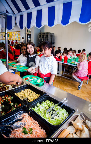 Zur Mittagszeit am UK staatliche Grundschullehrer und Kinder im Grundschulalter in der Grundschule Stockfoto