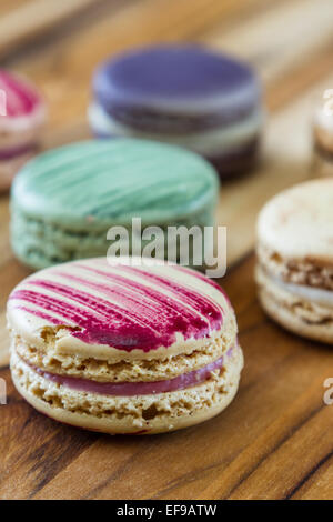 klassische französische Macarons handgefertigt und dekoriert in einer Vielzahl von Farben auf einem Holztisch Stockfoto