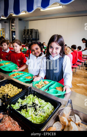 Zur Mittagszeit am UK staatliche Grundschullehrer und Kinder im Grundschulalter in der Grundschule Stockfoto