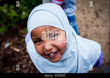 Glücklich lächelnd muslimische Mädchen Kopftuch auf dem Spielplatz der Grundschule in London W2 Stockfoto